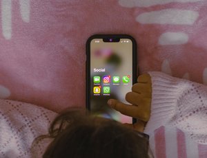 A child taps on a phone, which displays an app folder titled "social" containing apps like Instagram and Snapchat
